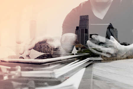 Double exposure of Designer hand using mobile payments online shopping,omni channel,in modern office wooden desk,London city buildings,eyeglassの写真素材