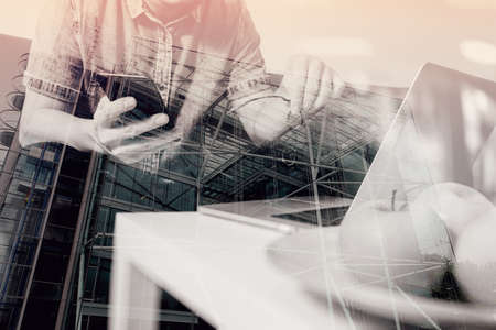 double exposure of hipster hand using laptop compter and mobile payments online business,eyeglasses,sitting on sofa in living room,green apples in wooden tray,London city buildingsの写真素材