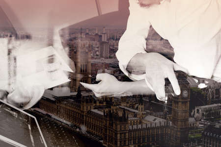 double exposure of hipster hand holding headphone,using digital tablet docking keyboard and mobile payments online business,omni channel,sitting on sofa in living room,London cityの写真素材