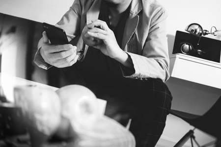 hipster hand using smart phone for mobile payments online business,sitting on sofa in living room,holding green apples in wooden tray,black and whiteの写真素材