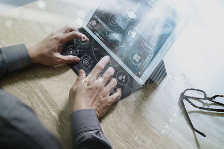 Designer Businessman hand using smart phone,mobile payments online shopping,omni channel,digital tablet docking keyboard computer in modern office on wooden desk,virtual interface icons screenの写真素材