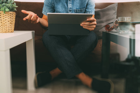 hipster hand using digital tablet docking keyboard,holding cradit card payments online business,sitting on sofa in living room,work at home concept,filter effectの写真素材