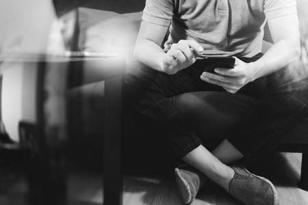 hipster hand using digital tablet docking keyboard and smart phone for mobile payments online business,omni channel,sitting on sofa in living room,green apples in wooden tray,black and whiteの写真素材