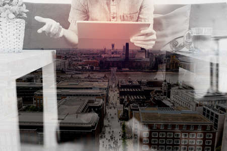 double exposure of hipster hand using digital tablet docking keyboard,holding cradit card payments online business,sitting on sofa in living room,work at home concept,London architecture cityの写真素材