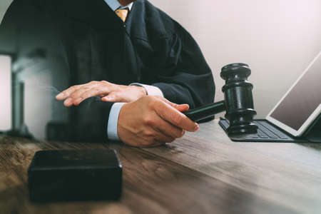 justice and law concept.Male judge in a courtroom with the gavel,working with digital tablet computer docking keyboard on wood table,filter effectの写真素材