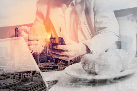 double exposure of hipster hand using smart phone,digital tablet docking keyboard,holding credit card payments online business,sitting on sofa in living room,work at home,London architecture cityの写真素材