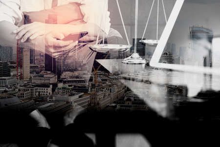 Double exposure of Justice and Law context.Male lawyer hand sitting on sofa and working with smart phone,digital tablet computer docking keyboard with gavel and document on living table at home,London architecture cityの写真素材