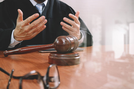 justice and law concept.Male judge in a courtroom with the gavel,working with smart phone,digital tablet computer docking keyboard,eyeglasses,on wood table,filter effectの写真素材