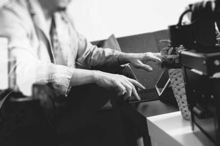hipster hand using smart phone,digital tablet docking keyboard,coffee cup, payments online business,sitting on sofa in living room,work at home concept,black and whiteの写真素材