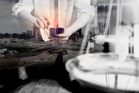 Double exposure of Justice and Law context.Male lawyer hand sitting on sofa and working with smart...