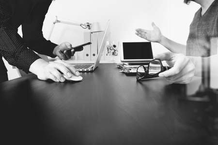 Business team meeting.Professional investor working new start up project and digital tablet docking keyboard and laptop computer with smart phone using and eyeglasses in modern office,black and whiteの写真素材
