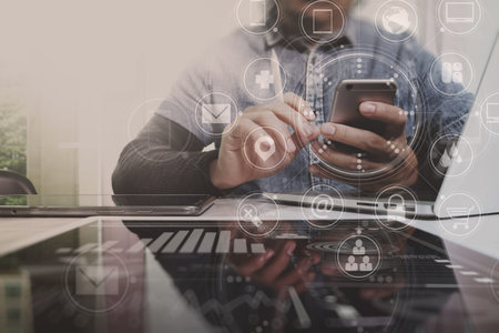 Designer using smart phone and digital tablet and laptop computer in modern office with virtual...