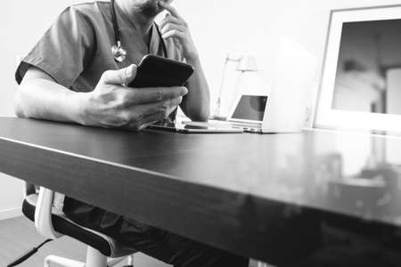 Medical technology concept.Doctor hand working with smart phone and laptop with digital tablet computer in modern clinic office,black and whiteの写真素材
