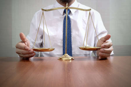 justice and law concept.Male lawyer in the office with brass scale on wooden tableの写真素材
