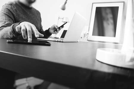 Designer using digital tablet and smart phone with latop computer in modern office,black and whiteの写真素材