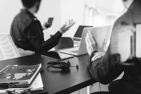 co working meeting,two businessman using VOIP headset with latop computer on desk in modern office as call center and customer service help desk concept,black and whiteの写真素材