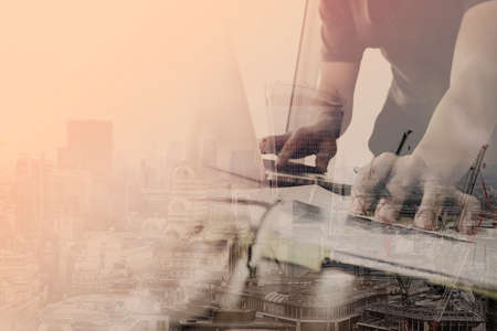 businessman working with laptop computer on wooden desk in modern office with London city exposureの写真素材