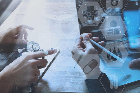 medical doctor hand working with smart phone,digital tablet computer,stethoscope eyeglass,on wooden...