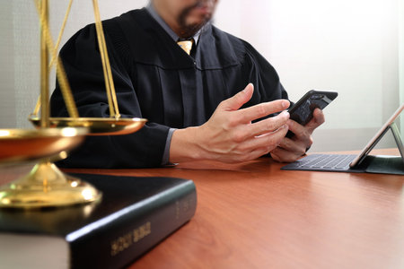 justice and law concept.Male judge in a courtroom with the gavel and working with smart phone and...