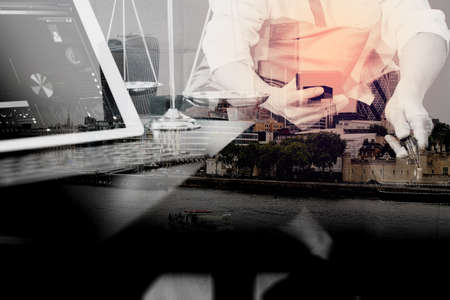 Double exposure of Justice and Law context.Male lawyer hand sitting on sofa and working with smart phone,digital tablet computer docking keyboard with gavel and document on living table at home,London architecture cityの写真素材