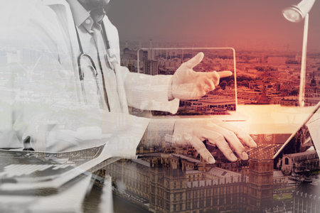 Double exposure of Medical technology concept. Doctor working with smart phone and stethoscope and digital tablet computer in modern office at hospital,London cityの写真素材