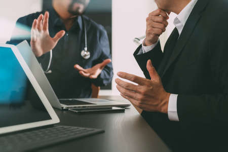 Medical co working concept,Doctor working with smart phone and digital tablet and laptop computer to meeting his team in modern office at hospitalの写真素材