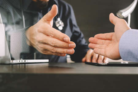 Medical and health care concept,Doctor and patient shaking hands in modern office at hospitalの写真素材