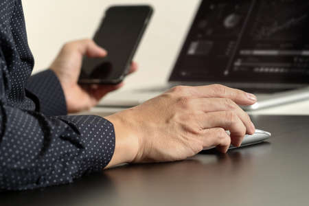 close up of businessman hand working with smart phone and laptop and digital tablet computer in modern officeの写真素材