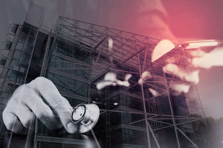 close up of smart medical doctor working with smart phone and stethoscope on dark wooden desk,London city exposureの写真素材