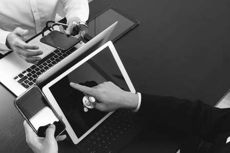 Medical co working concept,Doctor working with smart phone and digital tablet and laptop computer to meeting his team in modern office at hospital,black and whiteの写真素材