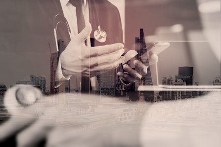 Medical co working concept,Doctor working with smart phone and digital tablet and laptop computer to meeting his team in modern office at hospital with London city exposureの写真素材