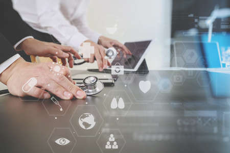 Medical co working concept,Doctor working with smart phone and digital tablet and laptop computer to meeting his team in modern office at hospital with virtual icon diagramの写真素材