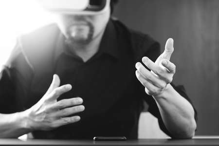 businessman wearing virtual reality goggles in modern office with mobile phone using with VR headset,black and whiteの写真素材