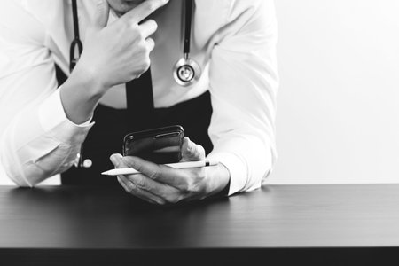 close up of businessman working with smart phone on wooden desk in modern office,black and whiteの写真素材