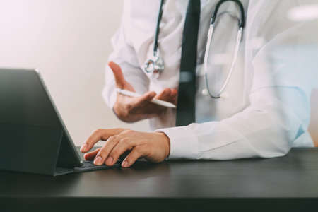 close up of smart medical doctor working with digital tablet computer and stylus pen and stethoscope on dark wooden desk with glass reflected viewの写真素材