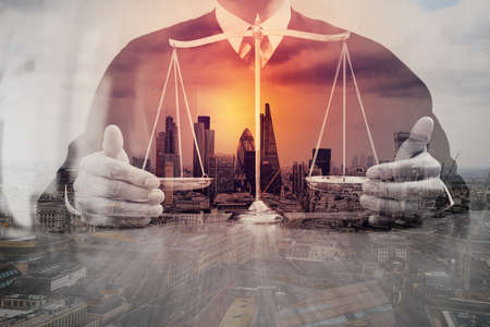 Double exposure of justice and law concept.Male judge in a courtroom with the balance scale on wood table,London cityの写真素材