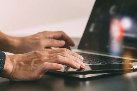 close up of businessman hand working with smart phone and laptop and digital tablet computer in modern office with glass reflected viewの写真素材