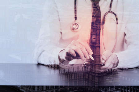 close up of businessman working with smart phone on wooden desk in modern office with London city exposureの写真素材