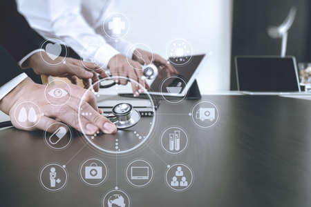 Medical co working concept,Doctor working with smart phone and digital tablet and laptop computer to meeting his team in modern office at hospital with virtual icon diagramの写真素材
