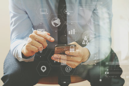 close up of businessman working with mobile phone and sitting on the chair in modern officewith...