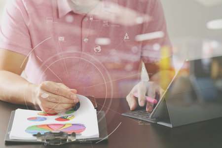 businessman in pink t-shirt working with digitl tablet computer and opening document on wooden desk...