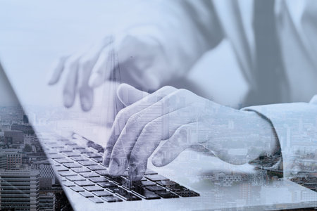 close up of businessman typing keyboard with laptop computer on wooden desk in modern office with London city exposureの写真素材