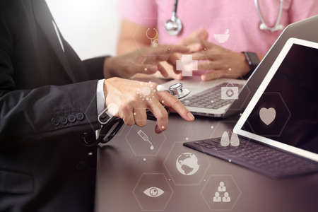 Medical co working concept,Doctor working with smart phone and digital tablet and laptop computer to meeting his team in modern office at hospital with virtual icon diagramの写真素材