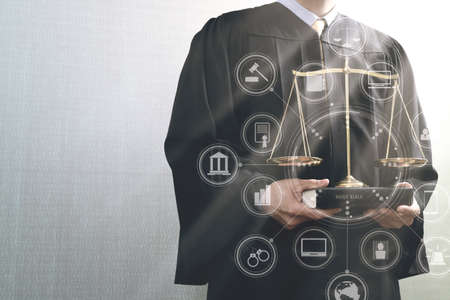 justice and law concept.Male judge in a courtroom with the balance scale and holy book with virtual computer interface graphic and icons diagramの写真素材