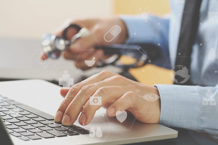 close up of smart medical doctor working with laptop computer and mobile phone and stethoscope on...