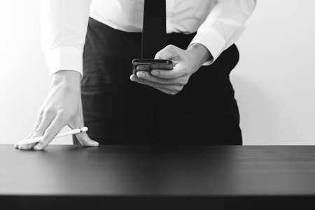 close up of businessman working with smart phone on wooden desk in modern office,black and whiteの写真素材