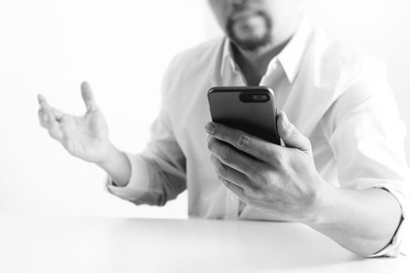 Big data analytics with business intelligence (BI) concept. businessman using mobile phone and laptop computer on white desk,black and whiteの写真素材
