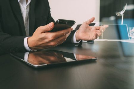 businessman working with smart phone and digital tablet and laptop computer in modern office with glass reflected viewの写真素材