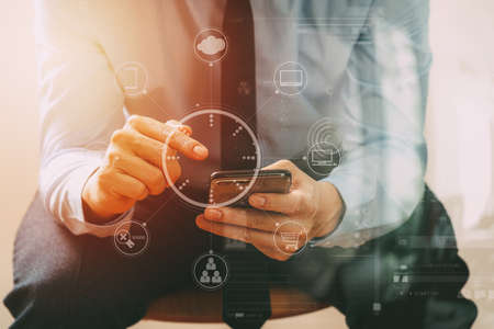 close up of businessman working with mobile phone and sitting on the chair in modern officewith virtual reality icon diagramの写真素材