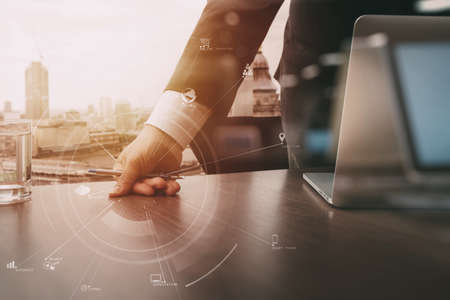 businessman working with mobile phone and digital tablet and laptop computer on wooden desk in modern office with VR icon and chart diagramの写真素材